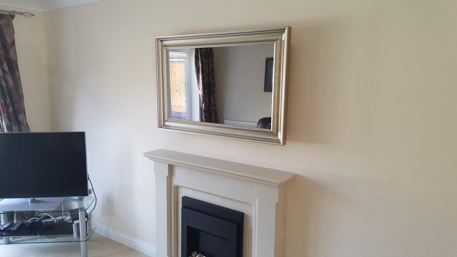 Gold-framed Mirror TV above an ornate white fireplace in a classic interior